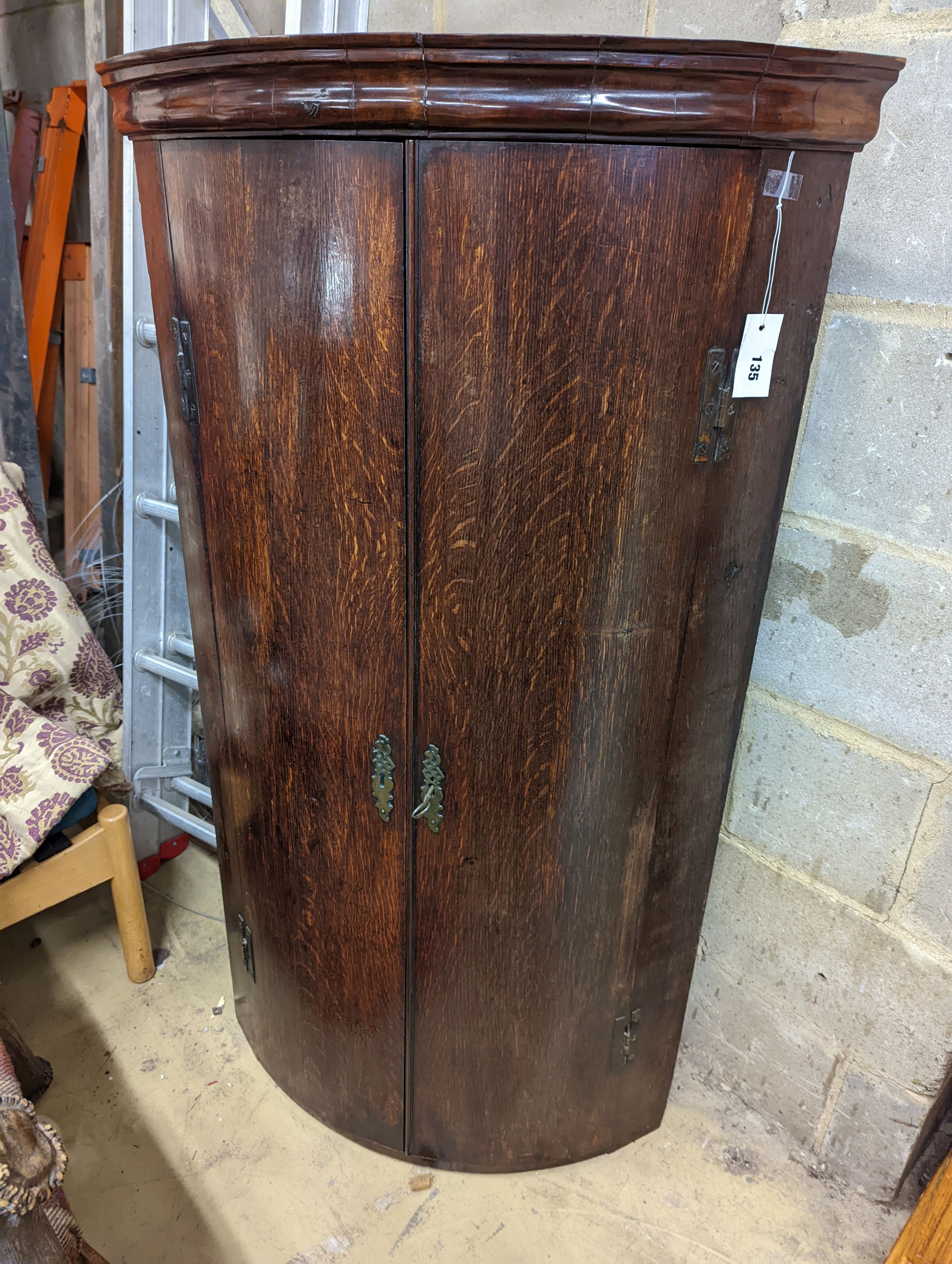 A George III oak bow-fronted hanging corner cabinet, width 73cm, depth 52cm, height 132cm